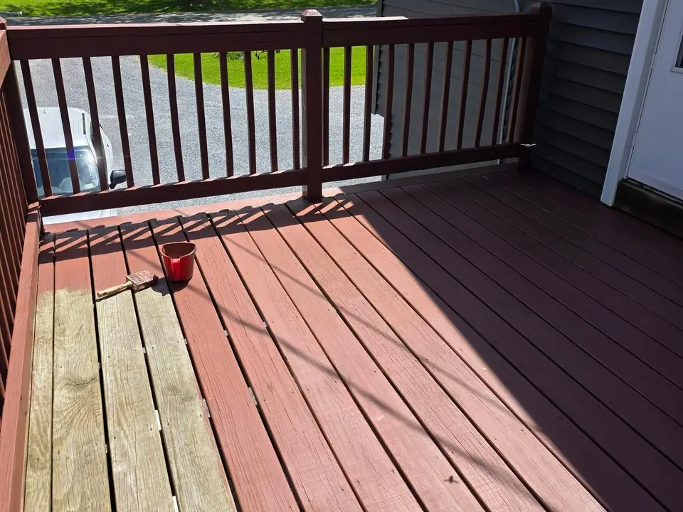 J.Lynn Painting repainting a deck in Vermont, half the boards finished in red-brown deck paint